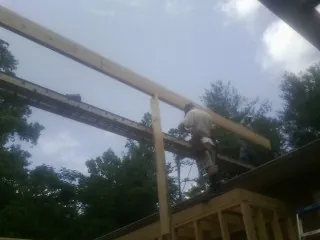 Carpenter setting a ridge beam over a new addition frame — Ice Dam Removal by Roofing Brothers in Burns