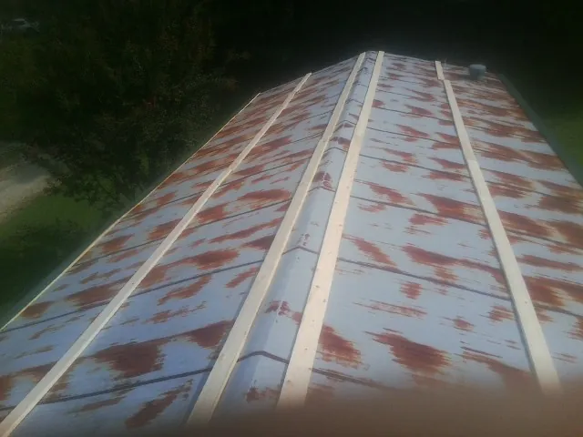 Rusted metal roof panels with new wood purlins before replacement — Storm Damage Roof Repair in Burns by Roofing Brothers