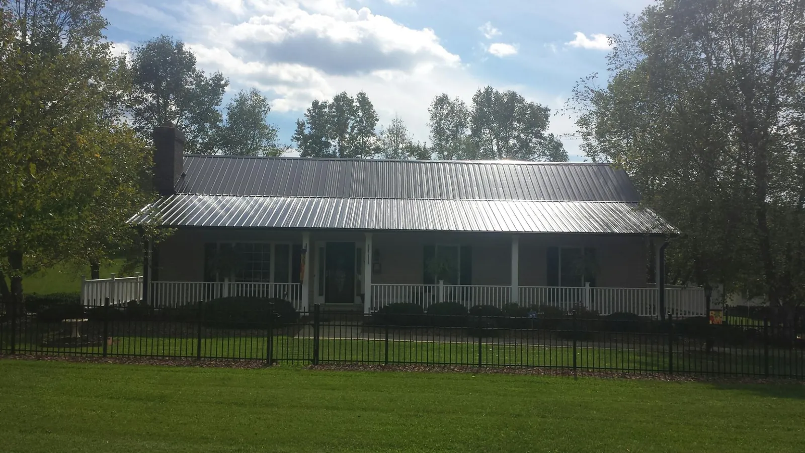 Gray metal roof on a brick ranch with a full width front porch — Gutter Guard Installation work by our crew in Burns