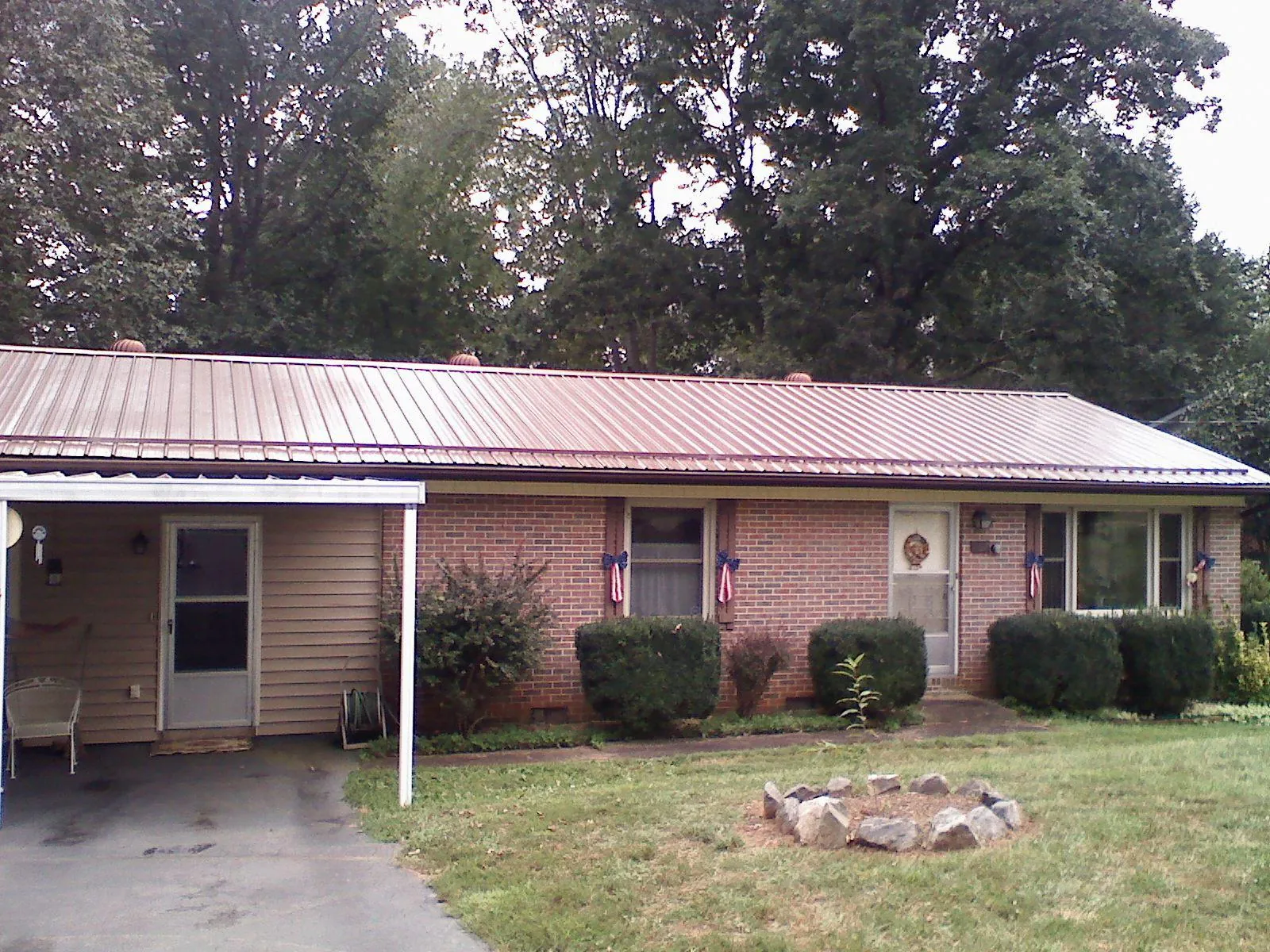 Bronze metal roof and carport on a brick ranch home — Roof Repair work by our crew in Burns