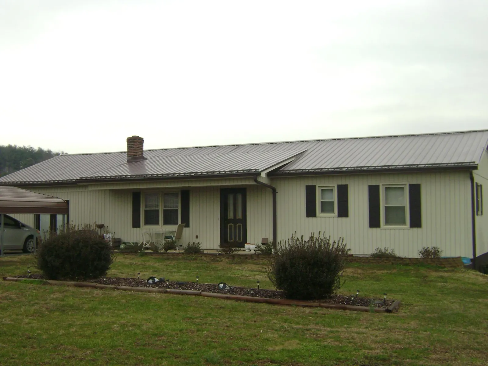 Brown metal roof on a cream sided ranch home with a brick chimney in Burns