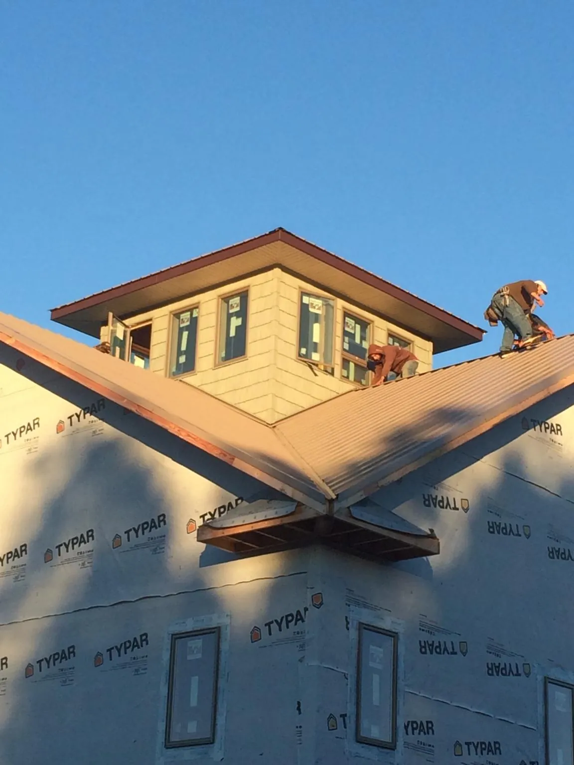 Roofers working around a rooftop cupola on a new metal roof at sunset — Roof Waterproofing in Burns by Roofing Brothers